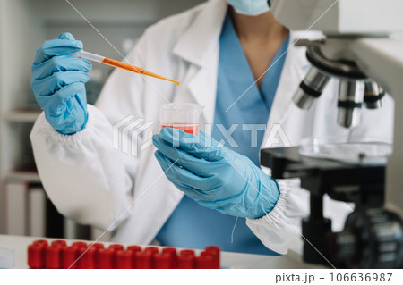 Medical or research scientist or doctor using looking at a test tube of clear solution in a lab or laboratory. 106636987