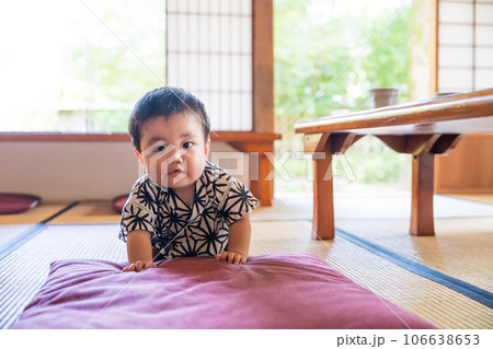 日本家屋の和室の畳で笑顔で座布団に乗ろうとする甚平姿の生後9か月の赤ちゃん 106638653