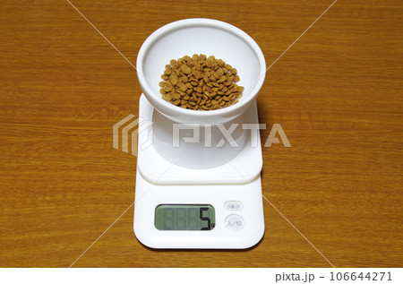 5gを示すデジタル上皿秤にキャットフードの入った器が載っている状態 106644271