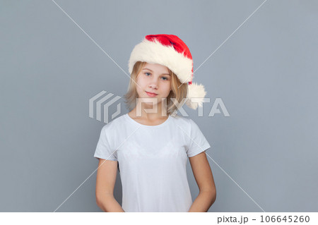 Cute young girl Santa on blue background, Christmas portrait Cute young girl Santa on blue background, Christmas portrait 106645260