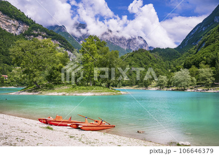 Amazing beautiful turquoise lake Tenno in Trentino region of Italy, surrouded by Alps mountains.  panoramic view with tiny island and canoe 106646379