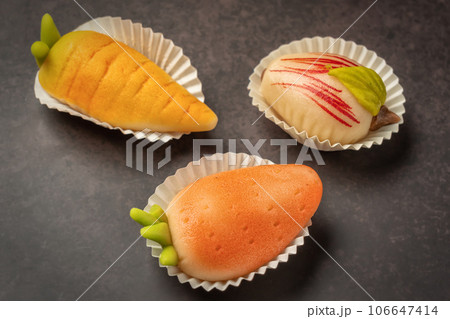 Portuguese marzipan delicacy in the shape of fruit apple, carrot, strawberry. Gourmet sweets from Algarve Portugal on a marble background close-up. 106647414
