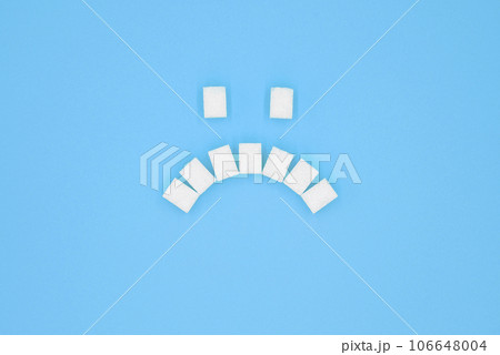 Sad face symbol, composed of cubes of sugar. 106648004