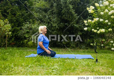 Relaxed athletic mature woman doing yoga on fitness mat outdoors. Relaxed athletic mature woman doing yoga on fitness mat outdoors. 106648148