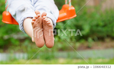 Closeup of happy kid sitting and swinging, sunny summer day, countryside background. Child feet barefoot. Copy space. Banner Closeup of happy kid sitting and swinging, sunny summer day, countryside background. Child feet barefoot. Copy space. Banner 106648312