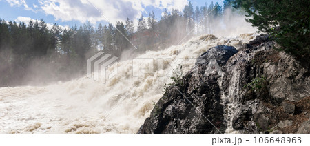 powerful stream during an idle discharge of water against the background of a building of a small hydroelectric power station 106648963