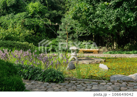 stone lantern on a small island in the middle of a pond in a Japanese garden 106649042
