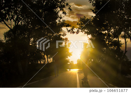Silhouette of a child playing surf skate on a golden sunshine day Silhouette of a child playing surf skate on a golden sunshine day 106651877