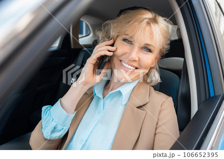 Female entrepreneur talks on smartphone sitting in vehicle Female entrepreneur talks on smartphone sitting in vehicle 106652395