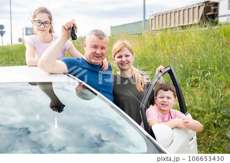 Happy parents with children posing together near car Happy parents with children posing together near car 106653430