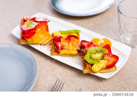 Puff pastry with custard cream, strawberries, tangerine and kiwi Puff pastry with custard cream, strawberries, tangerine and kiwi 106653616