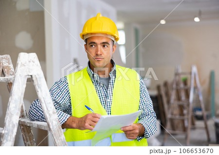 Young foreman checks the completed construction work and signs the documents 106653670