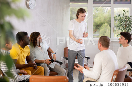 Guy talking to male colleagues gathered in office lounge room Guy talking to male colleagues gathered in office lounge room 106653912