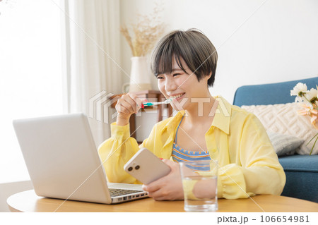 パソコンを見ながら身支度をする若い女性 106654981