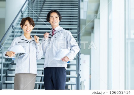 ヘルメットを持った作業服姿の男女 106655414