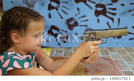 Little girl shoots at shooting range with gun. Outdoors entertainment for tourists in Thailand. Active leisure on vacation, traveling in Asia. Practice in shooting gallery safe legal pistol weapons. Little girl shoots at shooting range with gun. Outdoors entertainment for tourists in Thailand. Active leisure on vacation, traveling in Asia. Practice in shooting gallery safe legal pistol weapons. 106657821