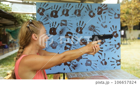 Woman shoots at shooting range with pneumatic gun. Outdoors entertainment for tourists in Thailand.Active leisure on vacation, traveling in Asia.Practice in shooting gallery safe legal pistol weapons. Woman shoots at shooting range with pneumatic gun. Outdoors entertainment for tourists in Thailand.Active leisure on vacation, traveling in Asia.Practice in shooting gallery safe legal pistol weapons. 106657824