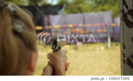 Outdoors entertainment for tourists in Thailand.Woman shoots at shooting range with pneumatic gun.Active leisure on vacation, traveling in Asia.Practice in shooting gallery safe legal pistol weapons. 106657866
