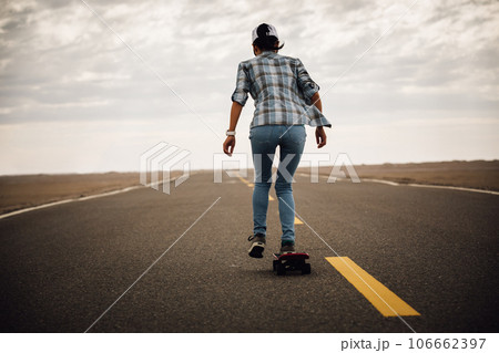 Asian woman skateboarder skateboarding on trail cross the desert Asian woman skateboarder skateboarding on trail cross the desert 106662397