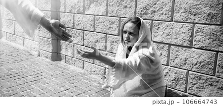 A girl in poor clothes sits on the ground 106664743