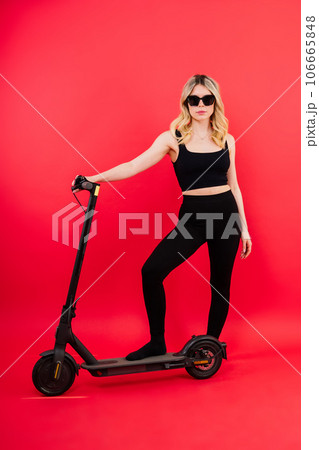 Happy young woman wear glasses riding electric scooter on background studio People lifestyle concept Happy young woman wear glasses riding electric scooter on background studio People lifestyle concept 106665848