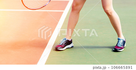 Legs of young girl in a closed tennis court with racket, sport shoes 106665891