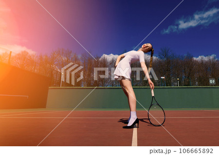 Sexy girl tennis player holding tennis racket on the court. Young woman is playing tennis. 106665892