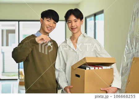Happy asian gay couple holding cardboard box and sowing key of new home. LGBTQ, relocation and real estate property Happy asian gay couple holding cardboard box and sowing key of new home. LGBTQ, relocation and real estate property 106668255