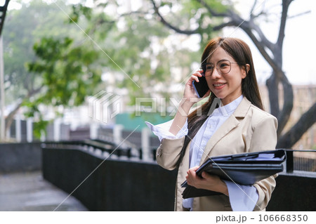 Modern businesswoman talking on mobile phone while standing outside office building office 106668350