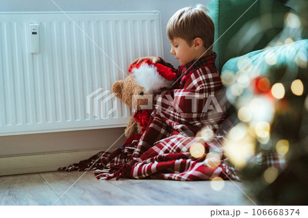 cute little boy wrapped id plaid sitting by heater 106668374