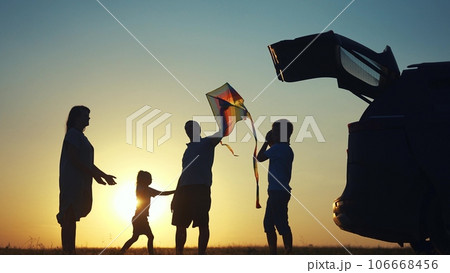 family traveling by car. family watching the sunset silhouette next to the car in the park. family playing kite ball. people in the park. family lifestyle car camping resting in nature 106668456