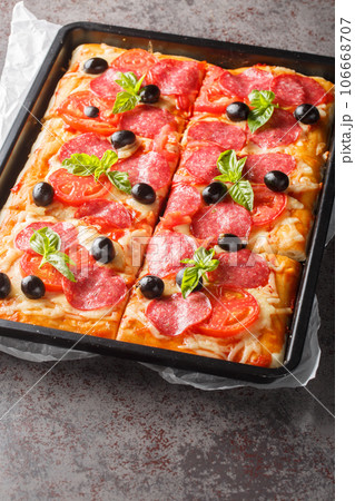 Pizza al Taglio with cheese, sausage, olives and tomatoes closeup on the tray. Vertical 106668707