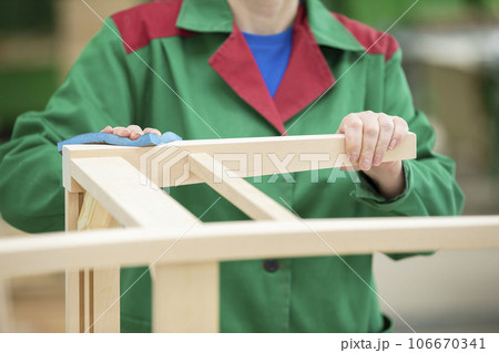 The hands of a woodworking plant worker grind wooden chairs from natural wood. The woodworking industry. 106670341