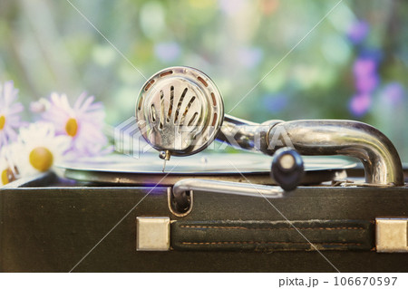 Vintage shot of a retro gramophone with a vinyl record and a romantic blurred bouquet of flowers. 106670597
