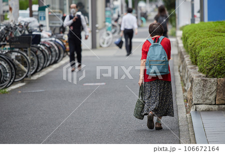 都市の街並みで歩くサラリーマンとシニア女性の姿 都市の街並みで歩くサラリーマンとシニア女性の姿 106672164