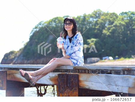 45 years old Russian woman drinking lemonad and sitting on pier 106672657