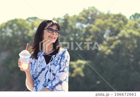 45 years old Russian woman drinking lemonad and sitting on pier 106672661