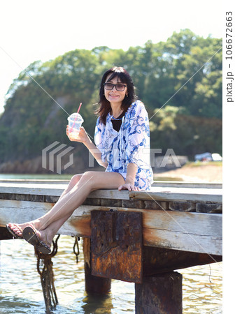 45 years old Russian woman drinking lemonad and sitting on pier 106672663
