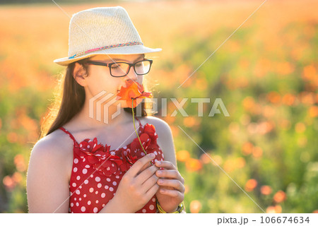 Portrait of a beautiful young girl in a hat in a poppy field Portrait of a beautiful young girl in a hat in a poppy field 106674634