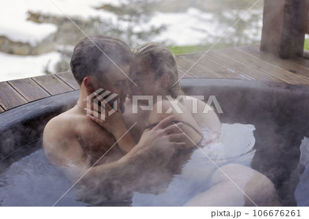 young couple hugging while sitting in a big vat 106676261