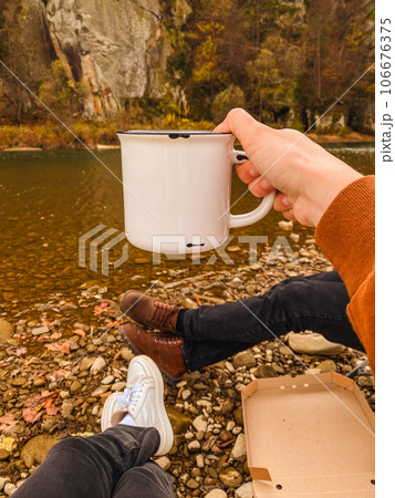 couple resting at autumn river side drinking warm tea 106676375