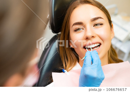The dentist demonstrates the proper use of dental floss to a young woman at the dental clinic The dentist demonstrates the proper use of dental floss to a young woman at the dental clinic 106676657