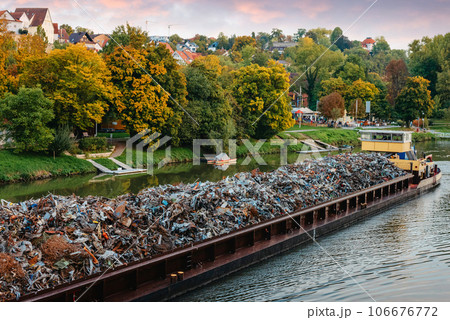 Transportation industry. Ship barge transports scrap metal and sand with gravel. Barge loaded with scrap metal is on the roadstead. Scrap metal transportation by water. Barge laden by metal salvage 106676772