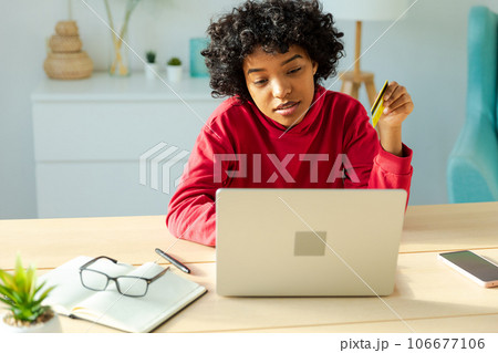 African american woman using laptop shopping online paying with gold credit card. Girl sitting at home buying on Internet enter credit card details. Online shopping ecommerce delivery service 106677106