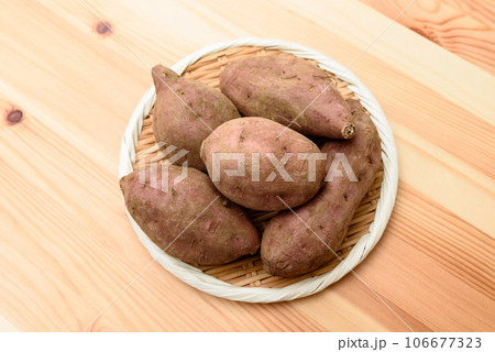 明るめ木目テーブルの上のザルに盛られた安納芋　サツマイモ 106677323