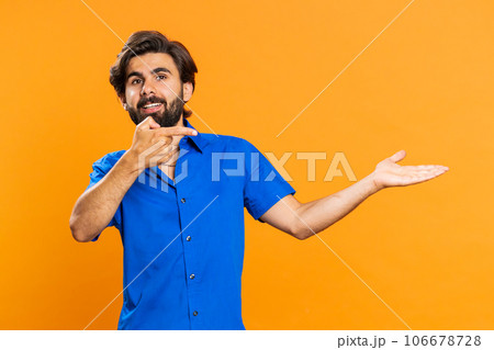 Young man showing thumbs up and pointing at left on blank space, place for your advertisement logo 106678728