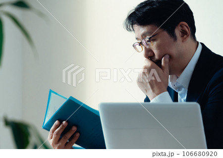 書類を見て悩むビジネスマン 106680920