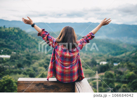 Rear view of young woman raised her hands when looking beautiful view of the nature's from Doi Chang in Chiang Rai province of Thailand. 106684042