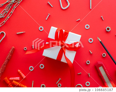 Construction tools and wrapped gift on red background Construction tools and wrapped gift on red background 106685187