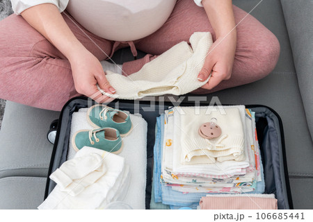 Anticipating the birth journey, pregnant woman meticulously packing, selecting essentials for her maternity hospital stay Anticipating the birth journey, pregnant woman meticulously packing, selecting essentials for her maternity hospital stay 106685441